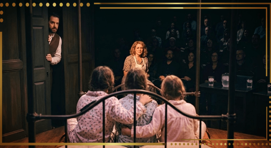 A digital AI creation and alt text by Google's Gemini of... A complex, low-angle backstage photograph taken from on top of an antique iron four-poster bed on the stage of Aquarius Rising (1980s). The camera looks over the iron footboard at the huddling, pajama-clad backs of three young orphan girls. In the mid-ground, the Irish Nanny character (medium-length blonde hair, floral dress, apron) is cowering, crying into a small cup, illuminated by a localized spotlight in a dark corner. The man from previous scenes peeks cautiously from around a solid wooden door frame in the backstage partition (stage left). The background is completely filled with a dense, sprawling audience seating area packed with dimly lit, silhouetted faces of patrons, some with faint reflections from glasses, emphasizing the packed house for the finale.